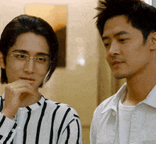 a man wearing glasses and a woman wearing a striped shirt are looking at something