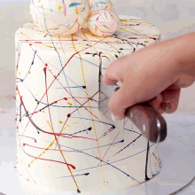 a person is cutting a cake with a knife that has paint splattered on it