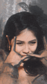 a woman covering her face with her hands and a feather on her head