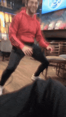 a man in a red adidas hoodie is dancing in a restaurant
