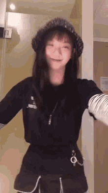 a woman wearing a hat and a black shirt is standing in a room .