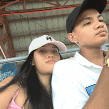 a man and a woman are posing for a picture and the woman is wearing a white hat with the letter a on it
