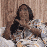 a woman is sitting on a couch with her hands in front of her face .