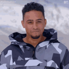 a man is wearing a camouflage jacket with the hashtag #exonthebeach