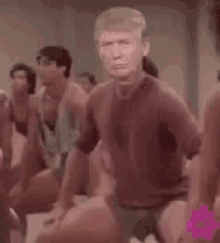 a man in a red shirt is dancing in front of a group of people in a gym .