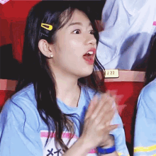 a girl in a blue shirt is clapping her hands in the audience .