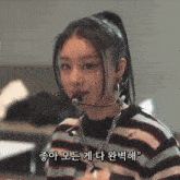 a woman wearing a striped sweater and a microphone with korean writing