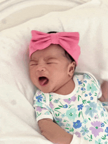 a newborn baby wearing a pink headband and a floral outfit