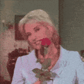 a woman in a blue jacket is holding a red rose