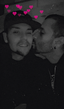 a man kissing another man on the cheek with hearts behind them