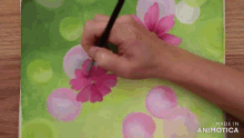 a person painting a pink flower on a green background