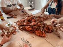 a man wearing an adidas shirt is sitting at a table eating crabs