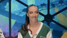 a woman wearing a green and white sweater is smiling and looking at the camera