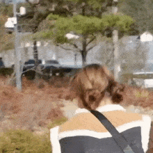 a woman is walking down a sidewalk with a bag on her shoulder .