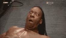 a shirtless man is laying on a wrestling mat with a wwe logo on his chest .