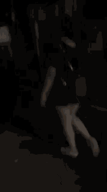 a woman in a black dress is walking in the dark