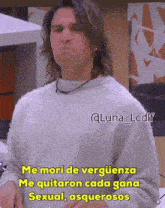 a man with long hair is wearing a grey sweater and has a caption that says me mori de verguenza