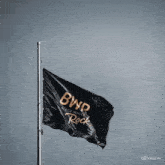 a black flag is flying in the wind with a quote in the background