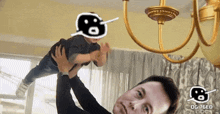 a man is holding a child in his arms with a chandelier behind him and a sticker that says og 76ed