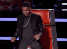 a man is sitting in a red chair on a stage giving a thumbs up .