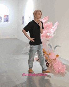 a man in a black shirt is standing in front of a pink flower arrangement