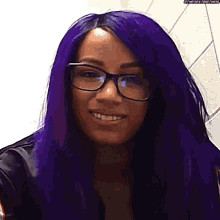 a woman with purple hair and glasses smiles for the camera .