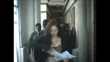 a woman in a leopard print top is holding a piece of paper in front of a group of people wearing masks .