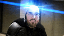 a man with a beard is wearing a superhero costume and has a blue light shining on his head