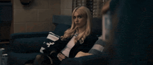 a woman is sitting on a couch with a pillow that says ' n ' on it