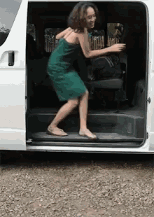 a woman in a green dress is getting out of the back of a van