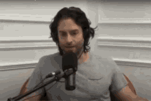 a man is sitting in front of a microphone while wearing headphones .