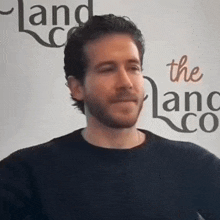 a man is standing in front of a sign that says the land co