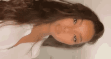 a woman with long brown hair is standing in front of a white wall .
