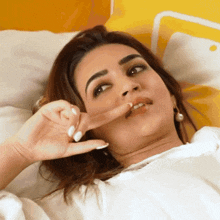a woman laying on a bed making a face with her finger in her mouth