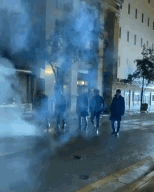 a group of people walking down a street with smoke coming out of it