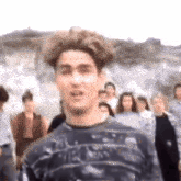 a man is standing in front of a crowd of people and looking at the camera .