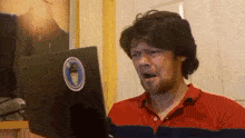 a man in a red shirt is looking at a laptop with a sticker on it that says ' captain ' on it