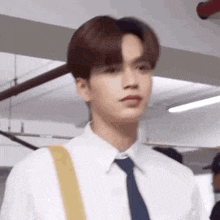 a young man in a white shirt and blue tie is looking at the camera .