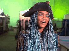 a woman with blue braids and a pirate hat is smiling
