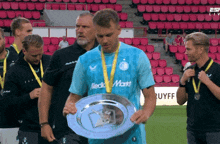 a man wearing a medal around his neck is holding a trophy on a field