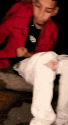 a blurry picture of a man wearing a red jacket and white jeans