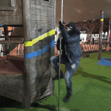 a man in a black jacket is climbing a pole in a playground