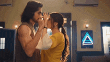a man and a woman are kissing in front of a neon sign that says a on it