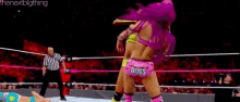 two women are wrestling in a ring and one of them is wearing a pink outfit .