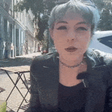 a woman with blue hair wearing a choker and a black jacket