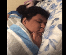 a man is sleeping on a bed with a blue and white striped blanket .