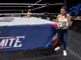 a woman in a wrestling ring stands in front of a banner that says elite