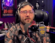 a man wearing glasses and headphones stands in front of a microphone with a badge that says police