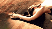 a woman is laying on her back on a wooden floor stretching her arms out .