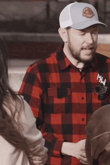 a man wearing a plaid shirt and a white hat with the letter hw on it